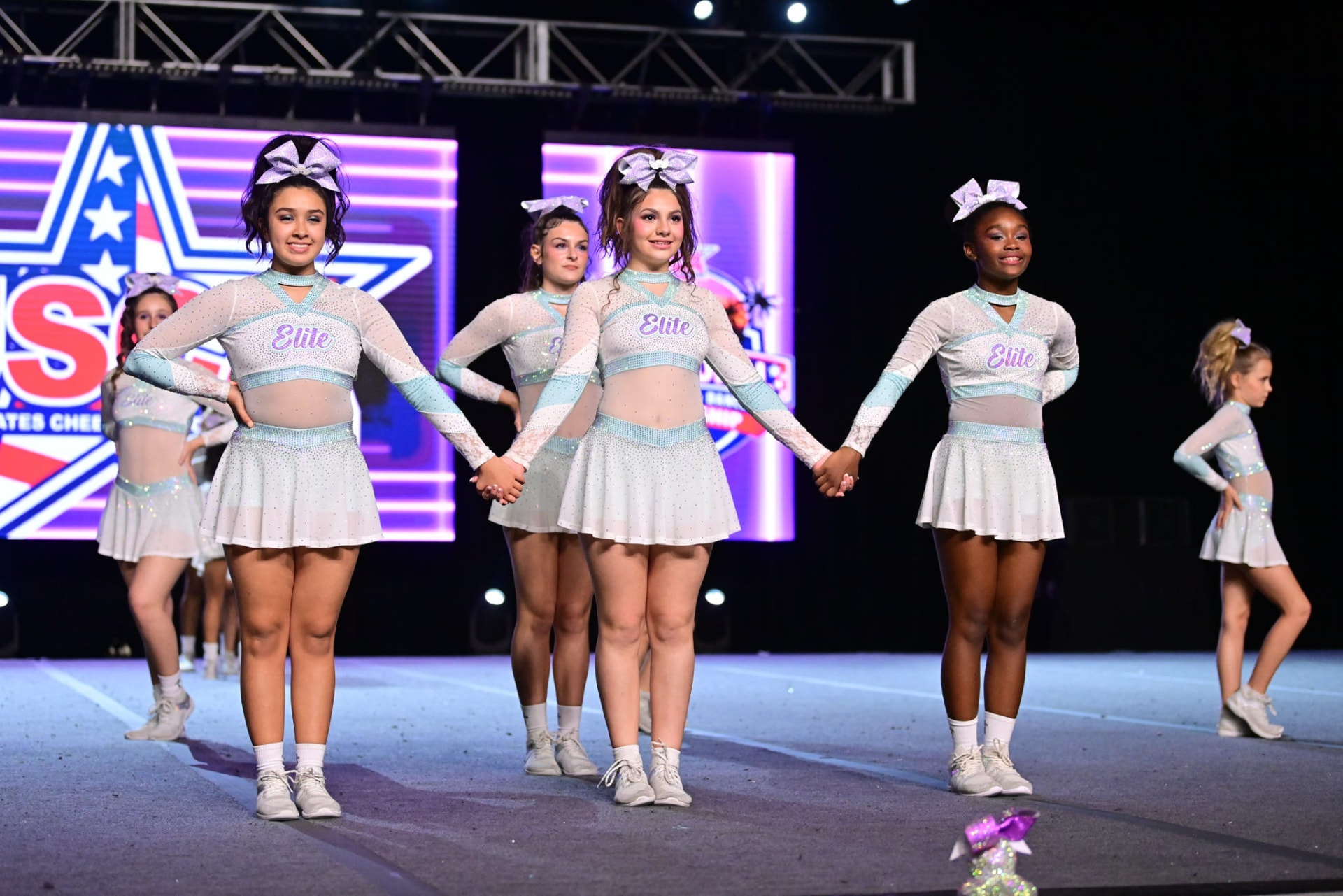 Elite Athletics cheerleaders holding hands on the competition floor